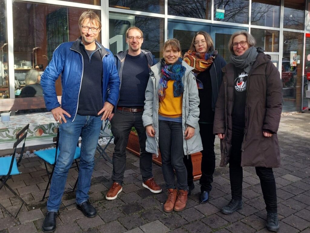 Fünf Menschen stehen nebeneinander und schauen in die Kamera.