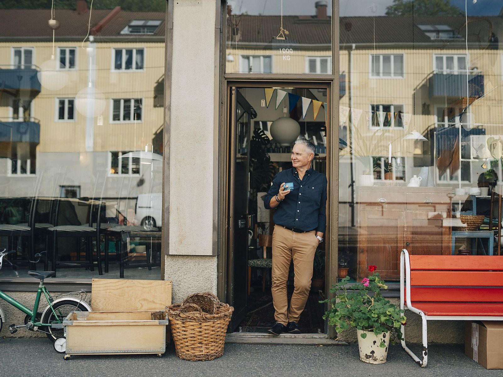 Ein Mann steht in einem Türrahmen und hält eine Tasse in der Hand.
