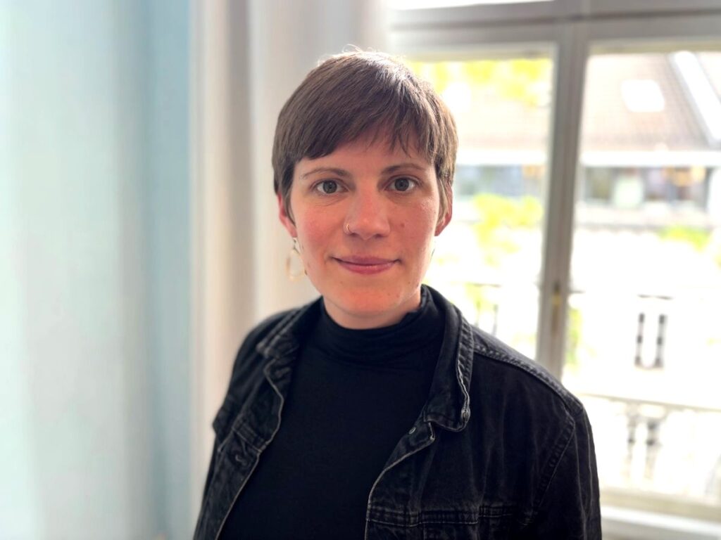 Eine Frau mit dunklem Oberteil und Jacke schaut in die Kamera
