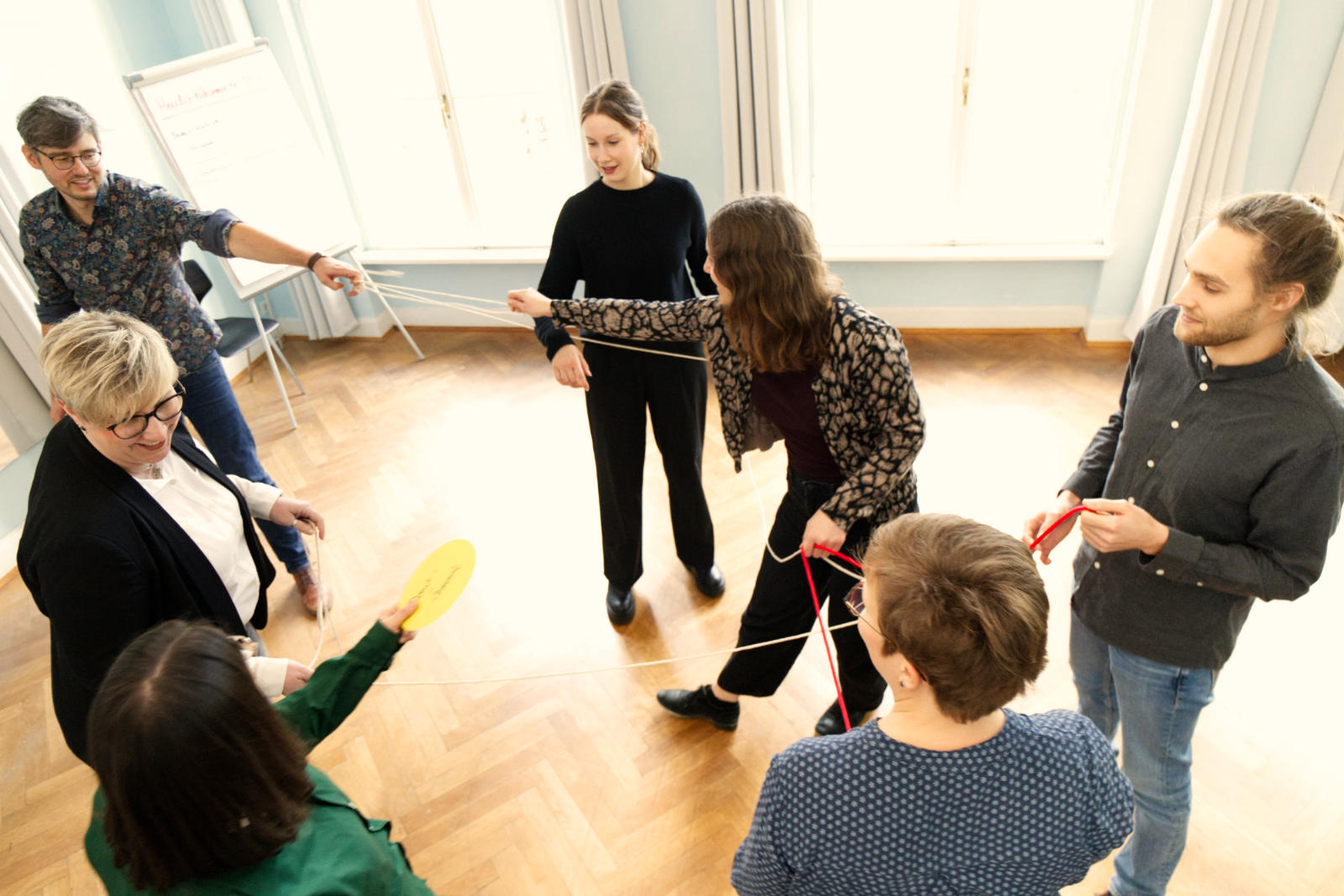 Sechs Menschen halten ein Seil zwischen sich