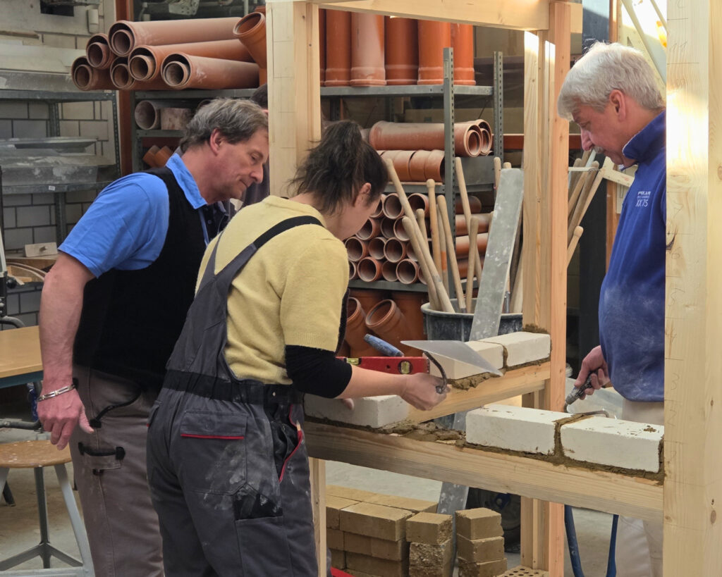 Zwei Männer und eine Frau arbeiten an einem Holzständerwerk